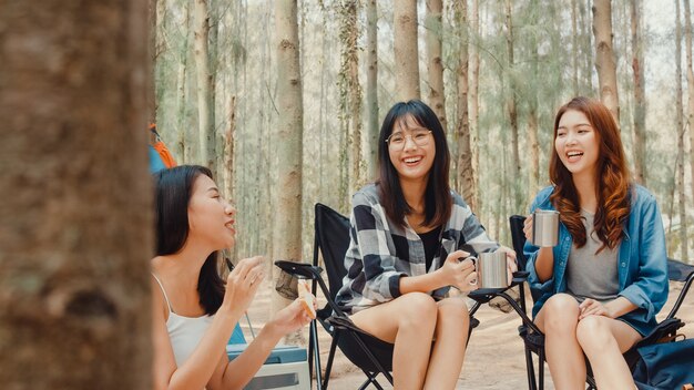 Gruppe junger asiatischer Camperfreunde, die auf Stühlen im Zelt im Wald sitzen?