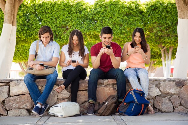 Gruppe junger Erwachsener, die ihre Smartphones in der Schule benutzen