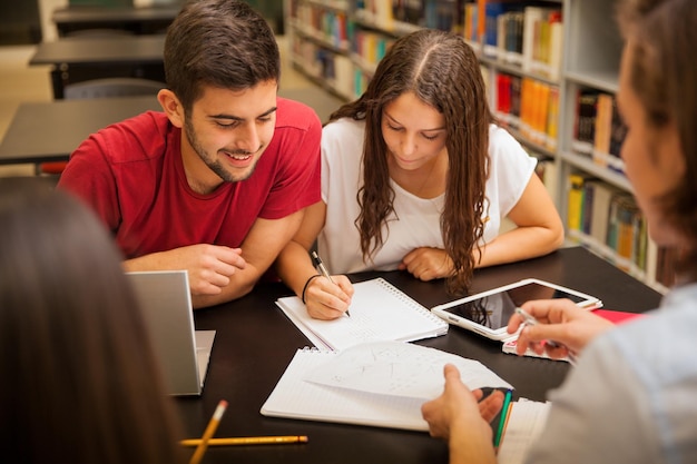 Gruppe junger Erwachsener, die zusammen lernen und sich in der Schulbibliothek amüsieren