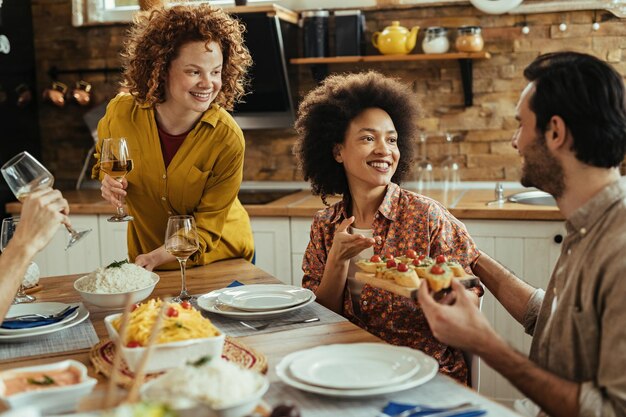 Gruppe junger glücklicher Menschen, die sich beim gemeinsamen Mittagessen im Speisesaal unterhalten