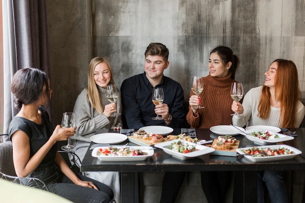 Gruppe junger Leute, die Abendessen und Wein zusammen genießen