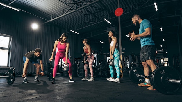 Gruppe junger leute, die drinnen im fitnessstudio trainieren beibehaltung des sportlichen lebensstils