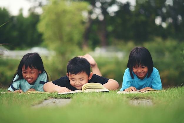 Gruppe Kinder, die das Lesen auf Rasenfläche liegen