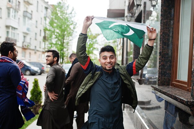 Gruppe pakistanischer Männer, die traditionelle Kleidung Salwar Kameez oder Kurta mit pakistanischen Flaggen tragen