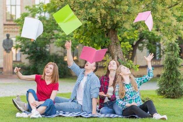 Gruppe Studenten, die Bücher in die Luft werfen