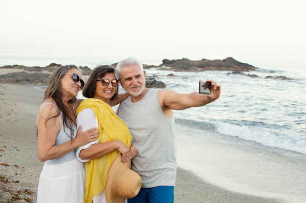 Gruppe von älteren Freunden, die Selfie mit Smartphone am Strand machen