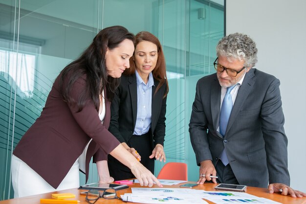 Gruppe von Fachleuten, die Papierberichte mit Diagrammen und Grafiken analysieren