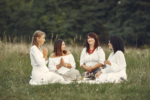 Gruppe von Frauen, die zusammen auf Wiese meditieren