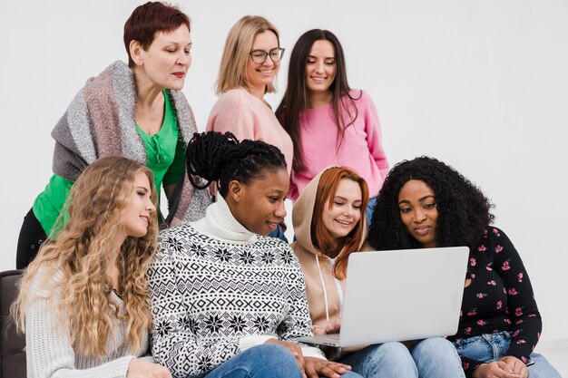 Gruppe von Frauen, die zusammen durch einen Laptop schauen