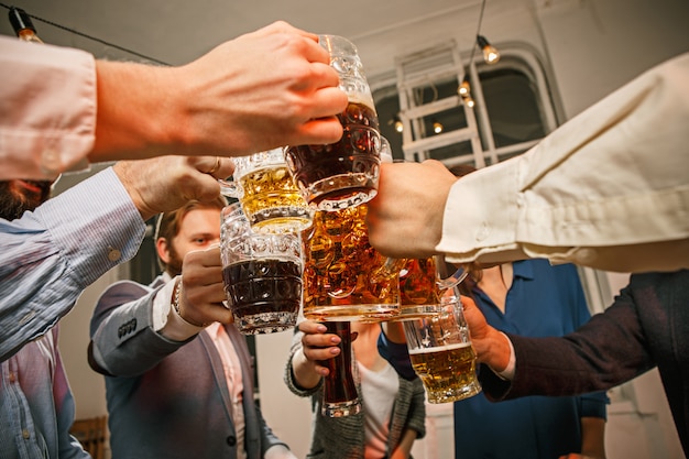 Gruppe von Freunden, die Abendgetränke mit Bier auf Holztisch genießen