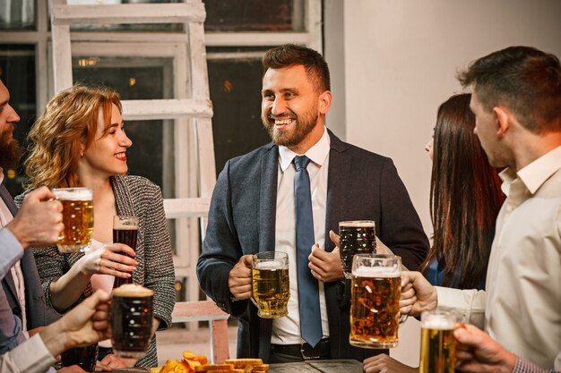 Gruppe von Freunden, die Abendgetränke mit Bier auf Holztisch genießen