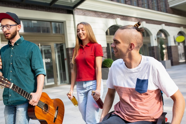 Gruppe von Freunden, die am Sommertag einen Spaziergang auf der Straße der Stadt machen