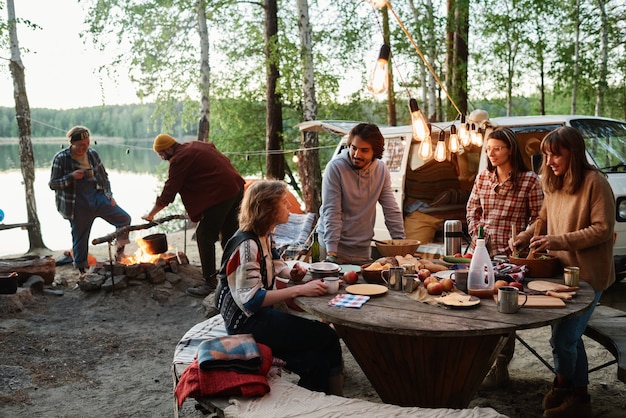 Gruppe von freunden, die bei einem picknick im wald zusammen essen und reden