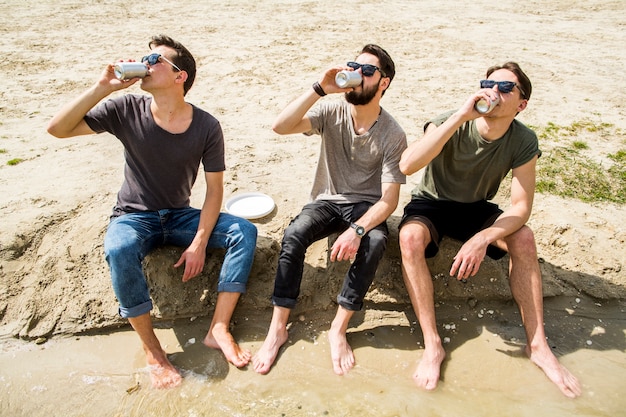 Gruppe von Freunden, die Bier am Strand trinken