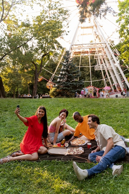 Gruppe von Freunden, die draußen am Riesenrad ein Selfie machen