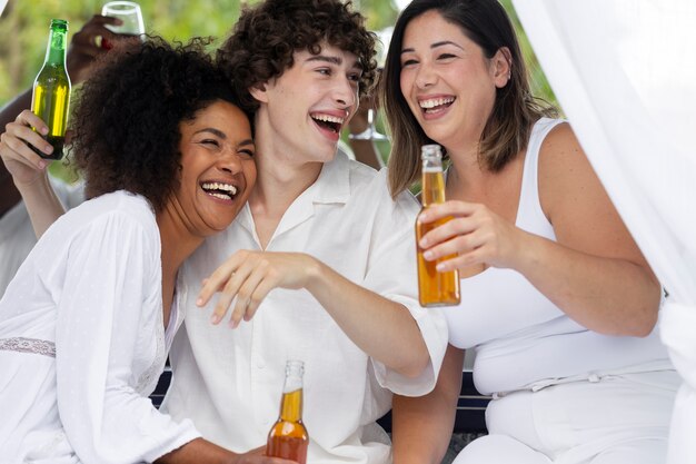 Gruppe von Freunden, die sich während einer weißen Party mit Getränken amüsieren