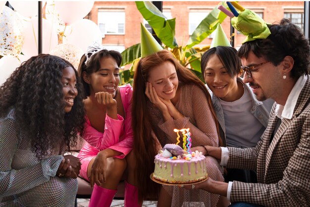 Gruppe von Freunden mit Kuchen auf einer Überraschungsgeburtstagsfeier