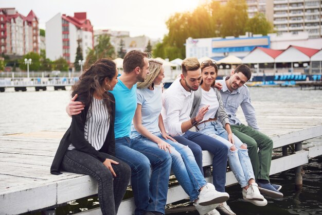 Gruppe von glücklichen jungen Freunden auf dem Pier, Freude am Spielen schafft emotionales Leben.