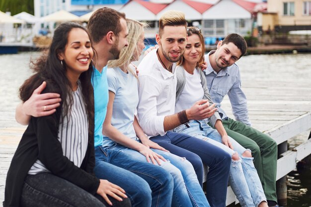 Gruppe von glücklichen jungen Freunden auf dem Pier, Freude am Spielen schafft emotionales Leben.