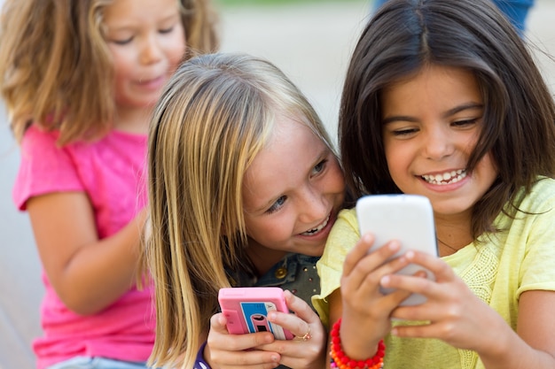 Gruppe von Kinder im Chat mit Smartphones im Park.