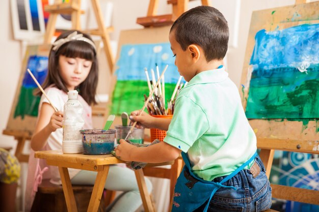 Gruppe von Kindern, die während des Kunstunterrichts in der Schule an einem Gemälde einer Landschaft arbeiten