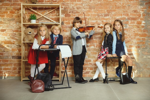 Gruppe von Kindern, die Zeit nach der Schule zusammen verbringen. Hübsche Freunde, die sich nach dem Unterricht ausruhen, bevor sie anfangen, Hausaufgaben zu machen. Modernes Loft-Interieur. Schulzeit, Freundschaft, Bildung, Zusammengehörigkeitskonzept.