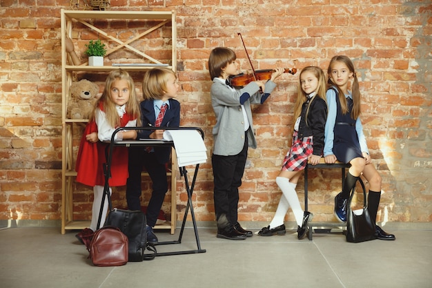 Gruppe von Kindern, die Zeit nach der Schule zusammen verbringen. Hübsche Freunde, die sich nach dem Unterricht ausruhen, bevor sie anfangen, Hausaufgaben zu machen