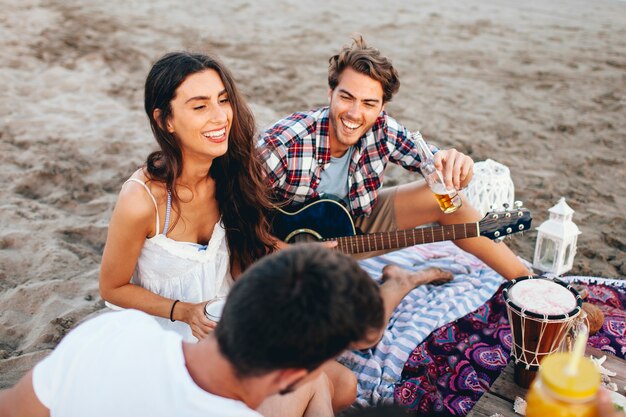 Gruppe von lachenden Freunden sitzen am Strand