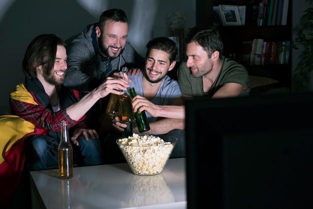 Gruppe von männern, die bier trinken und fußball im fernsehen schauen