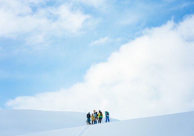 Gruppe von Menschen, die in den Bergen wandern, die im Schnee unter dem schönen blauen Himmel bedeckt sind