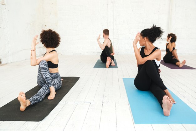 Kostenloses Foto gruppe von menschen, die yoga im fitnessstudio tun, das auf trainingsmatten sitzt