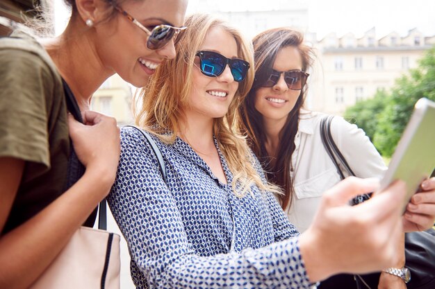 Gruppe von stilvollen Frauen, die in der Stadt genießen und ein digitales Tablet verwenden