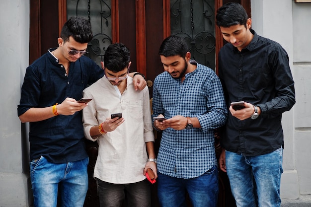 Gruppe von vier indischen Ethnizität Freundschaft Zusammengehörigkeit bemannt Technologie- und Freizeittypen mit Telefonen