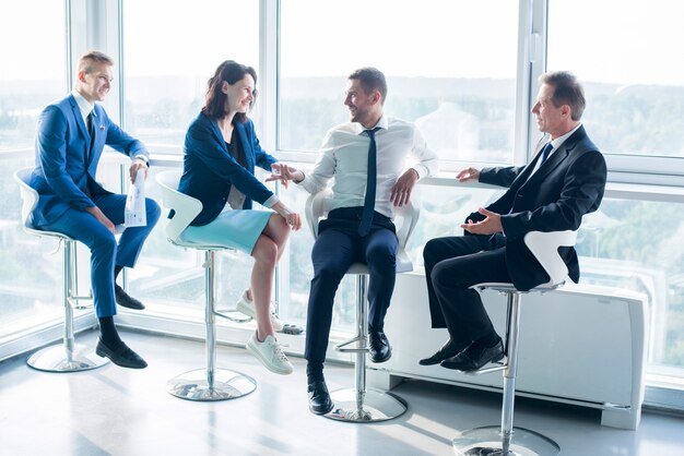 Gruppe Wirtschaftler, die auf Schemel im Büro sitzen