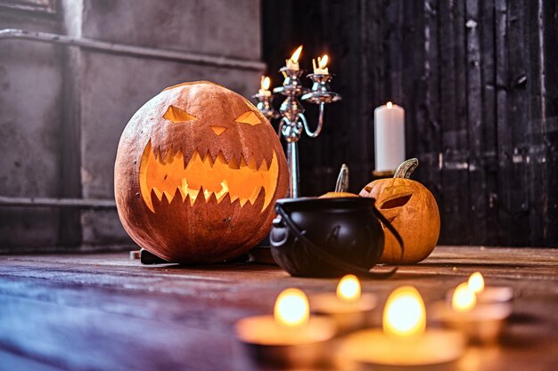 Gruselige Kürbisse und Kerzen auf einem Holzboden in einem alten Haus. Halloween-Konzept.