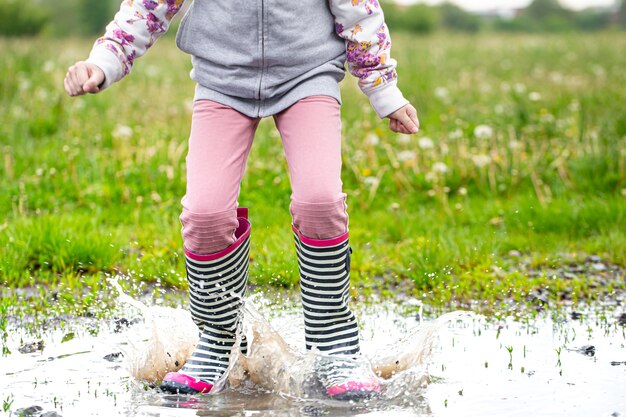 Gummistiefel in einer Pfütze beim Springen mit Wasserspritzern