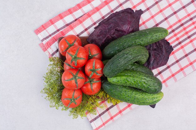 Gurken, Gemüse und Tomaten auf Tischdecke.