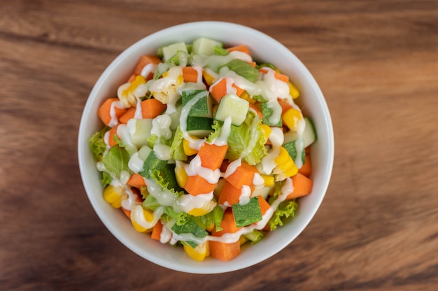 Gurkensalat, Mais, Karotte und Salat in einer weißen Tasse.