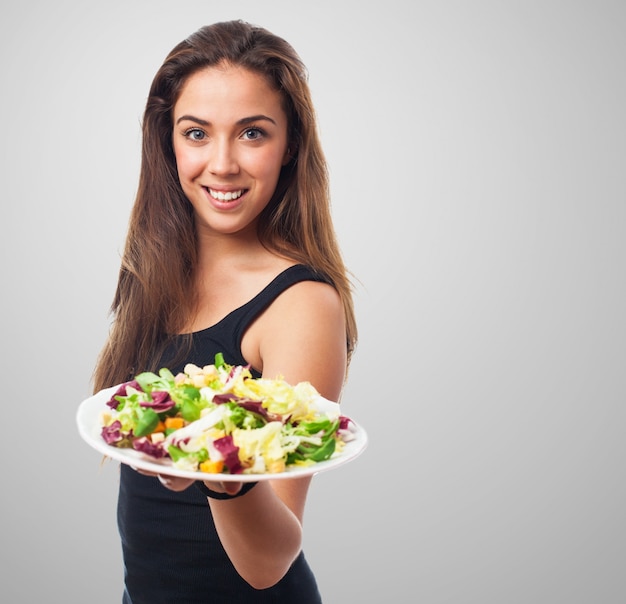 Gut aussehende Modell einen Teller mit Salat hält