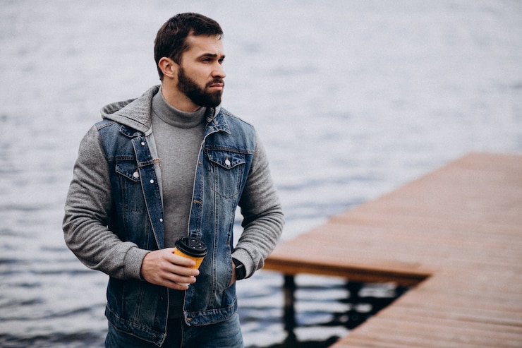 Kostenlose Foto gut aussehender bärtiger mann, der kaffee durch den fluss im park trinkt