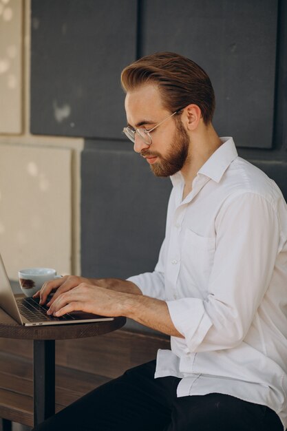 Gut aussehender Geschäftsmann, der online am Computer aus dem Café arbeitet?