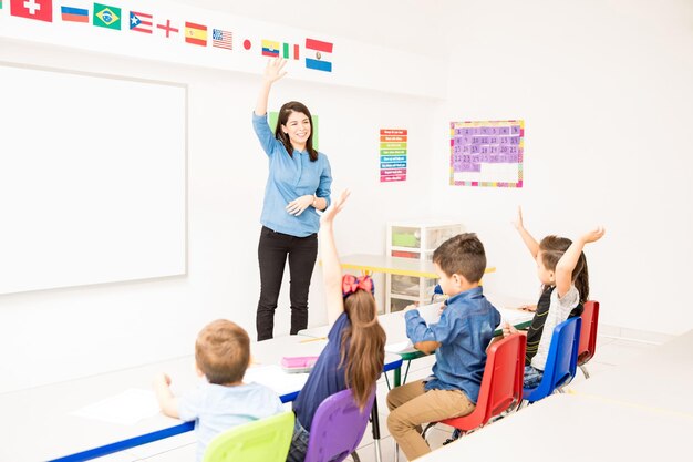 Gut aussehender Latein-Vorschullehrer, der die Schüler bittet, ihre Hand zu heben, um am Unterricht teilzunehmen