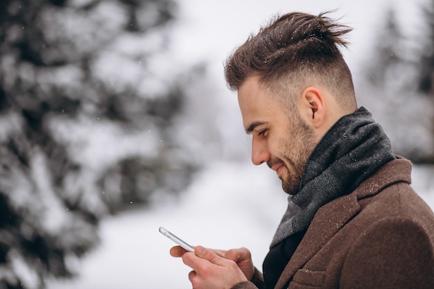 Gut aussehender Mann, der am Telefon in einem Winterpark spricht