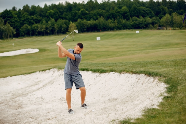 Gut aussehender Mann, der Golf auf einem Golfplatz spielt