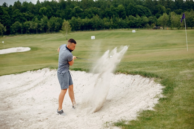 Gut aussehender Mann, der Golf auf einem Golfplatz spielt