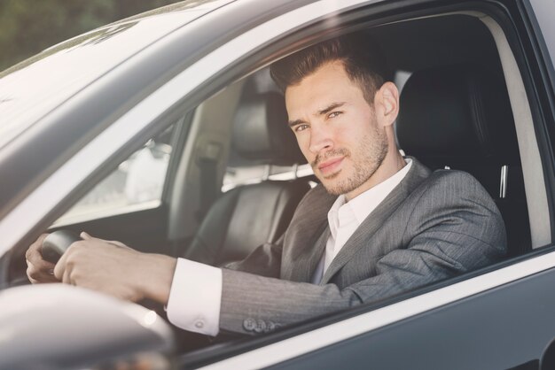 Gut aussehender Mann, der im Auto betrachtet Kamera sitzt