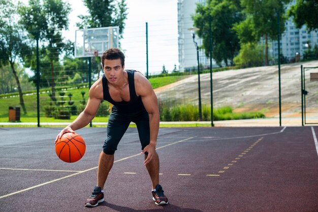 Gut aussehender Mann, der mit dem Basketballball spielt