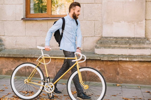 Gut aussehender Mann, der mit Fahrrad geht