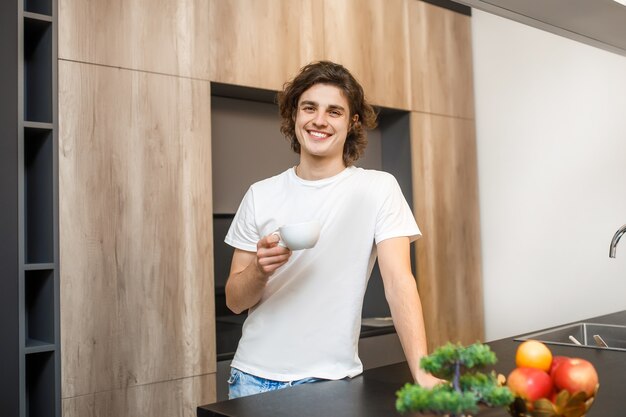 Gut aussehender Mann, der Morgenkaffee in der Küche trinkt