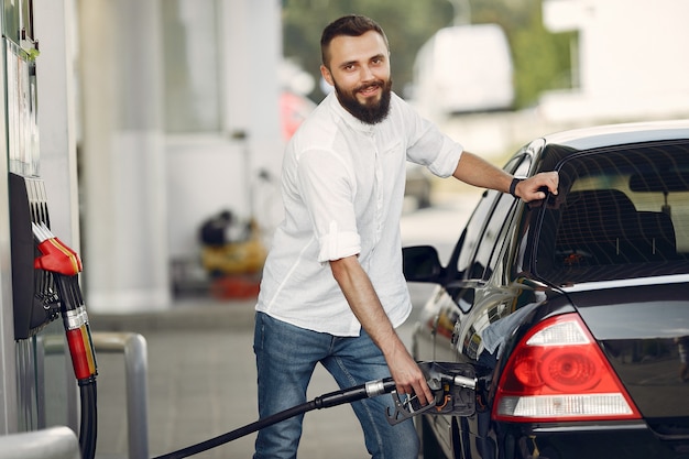 Gut aussehender Mann gießt Benzin in Tank des Autos